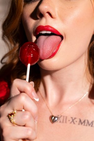 Sophia Mae in lace robe teases with lollipop on black leather couch photo 2