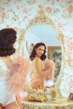 Bryona Ashly poses in pink feather robe on white bedding photo 8